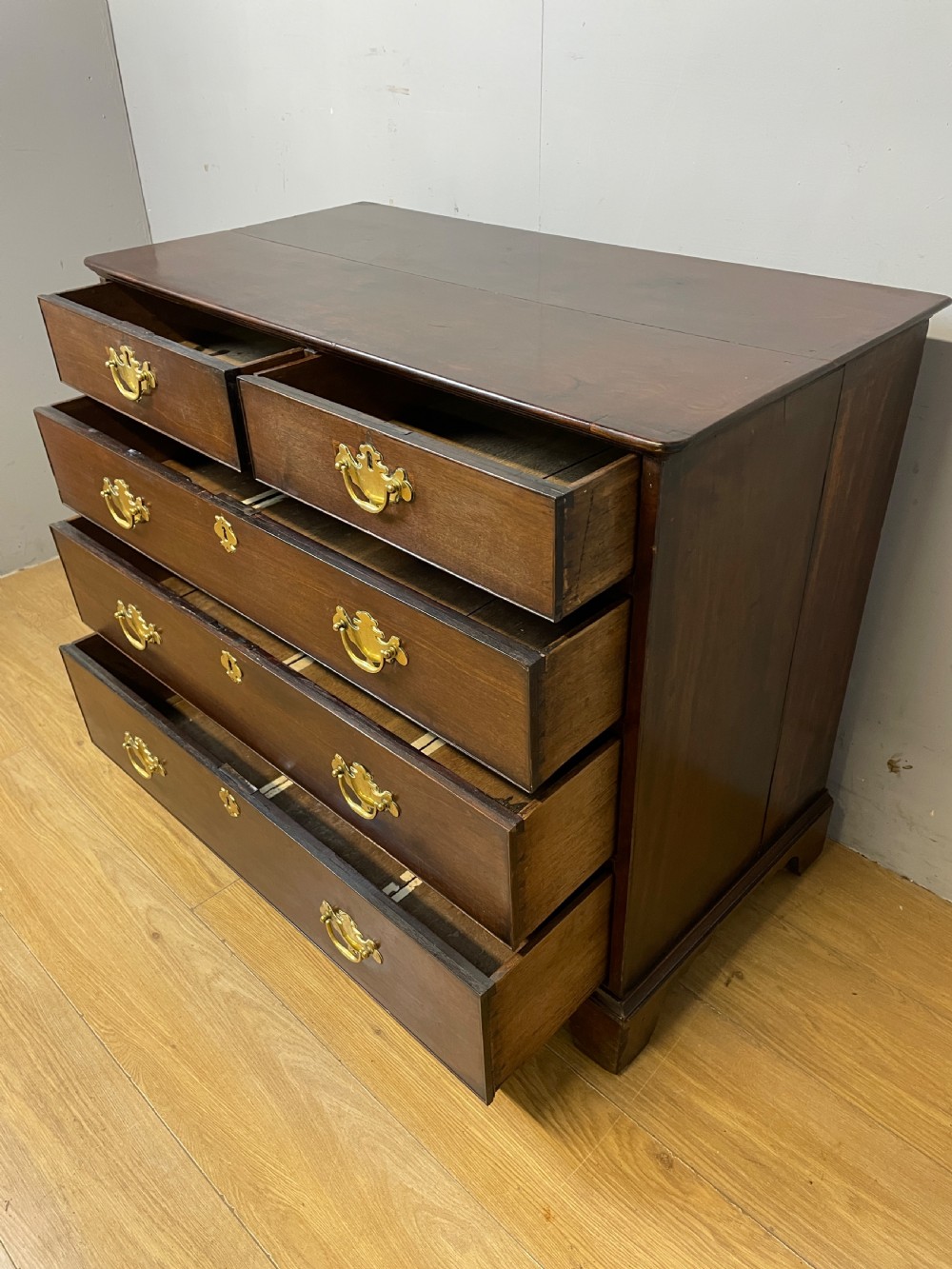 A late 18th-century Georgian solid mahogany four-height chest of drawers with two short over three long drawers, brass handles, and bracket feet. View VIII