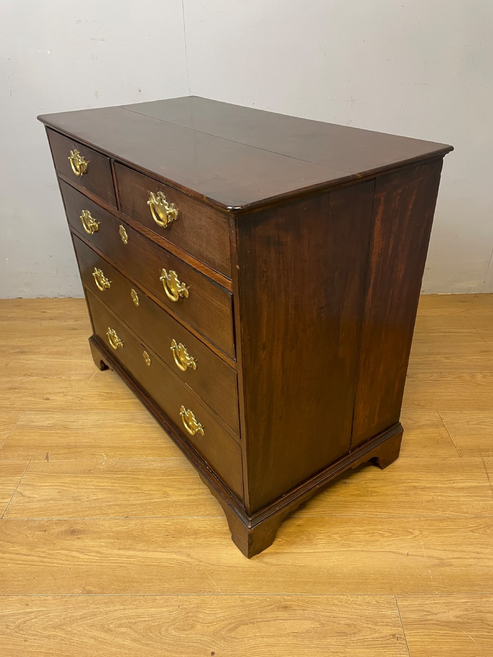 A late 18th-century Georgian solid mahogany four-height chest of drawers with two short over three long drawers, brass handles, and bracket feet. View IX