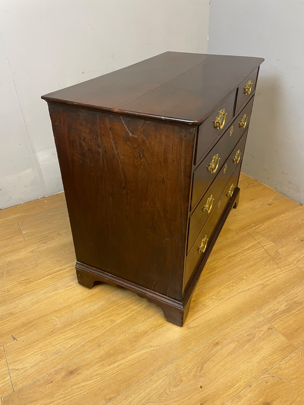 A late 18th-century Georgian solid mahogany four-height chest of drawers with two short over three long drawers, brass handles, and bracket feet. View X