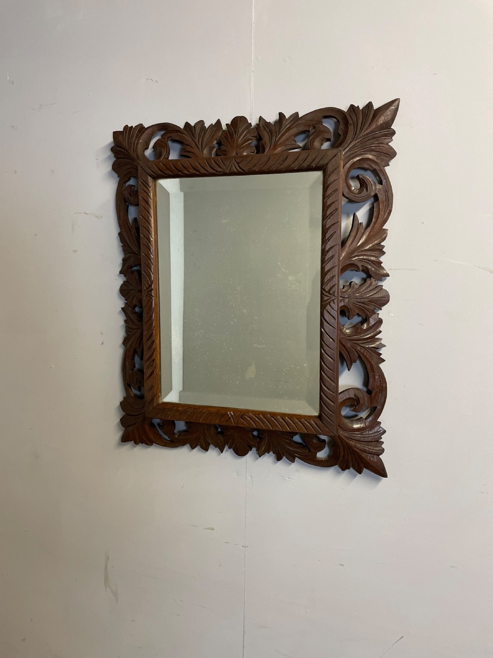 A rectangular 19th-century wall mirror with a bevelled glass plate set inside a deeply carved oak frame featuring acanthus leaves.
