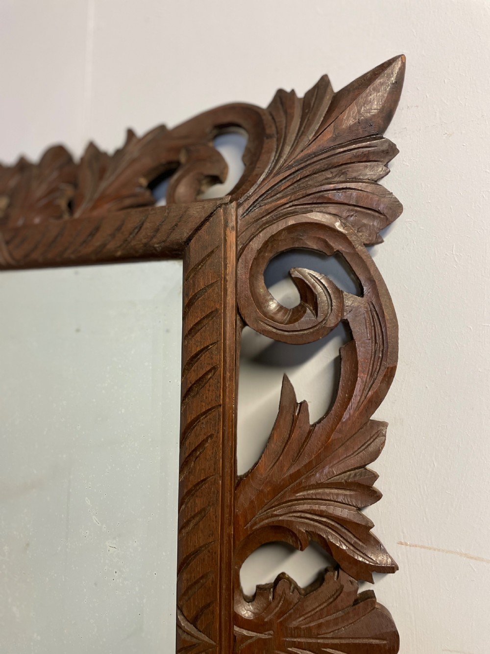 A rectangular 19th-century wall mirror with a bevelled glass plate set inside a deeply carved oak frame featuring acanthus leaves. View IV