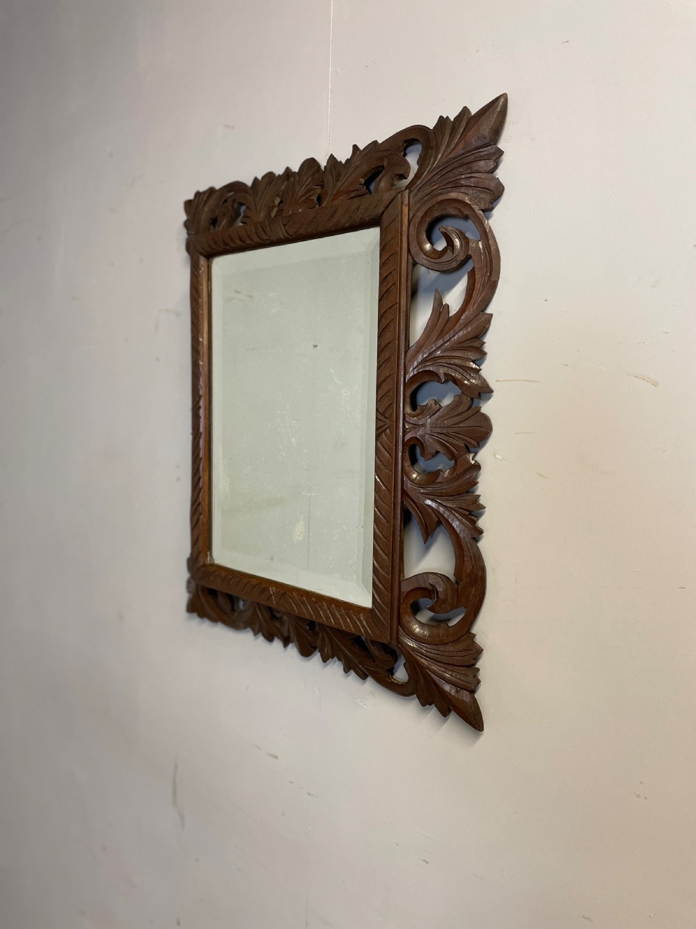 A rectangular 19th-century wall mirror with a bevelled glass plate set inside a deeply carved oak frame featuring acanthus leaves. View V