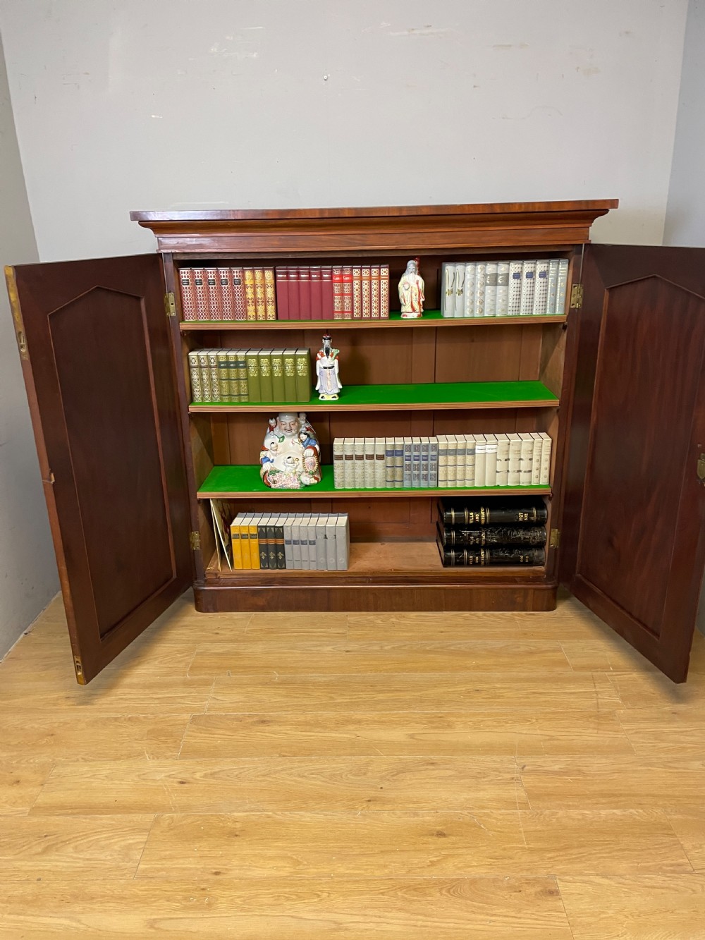 A nineteenth-century flame mahogany two-door library cupboard with arched door panels and a plinth base. View IX