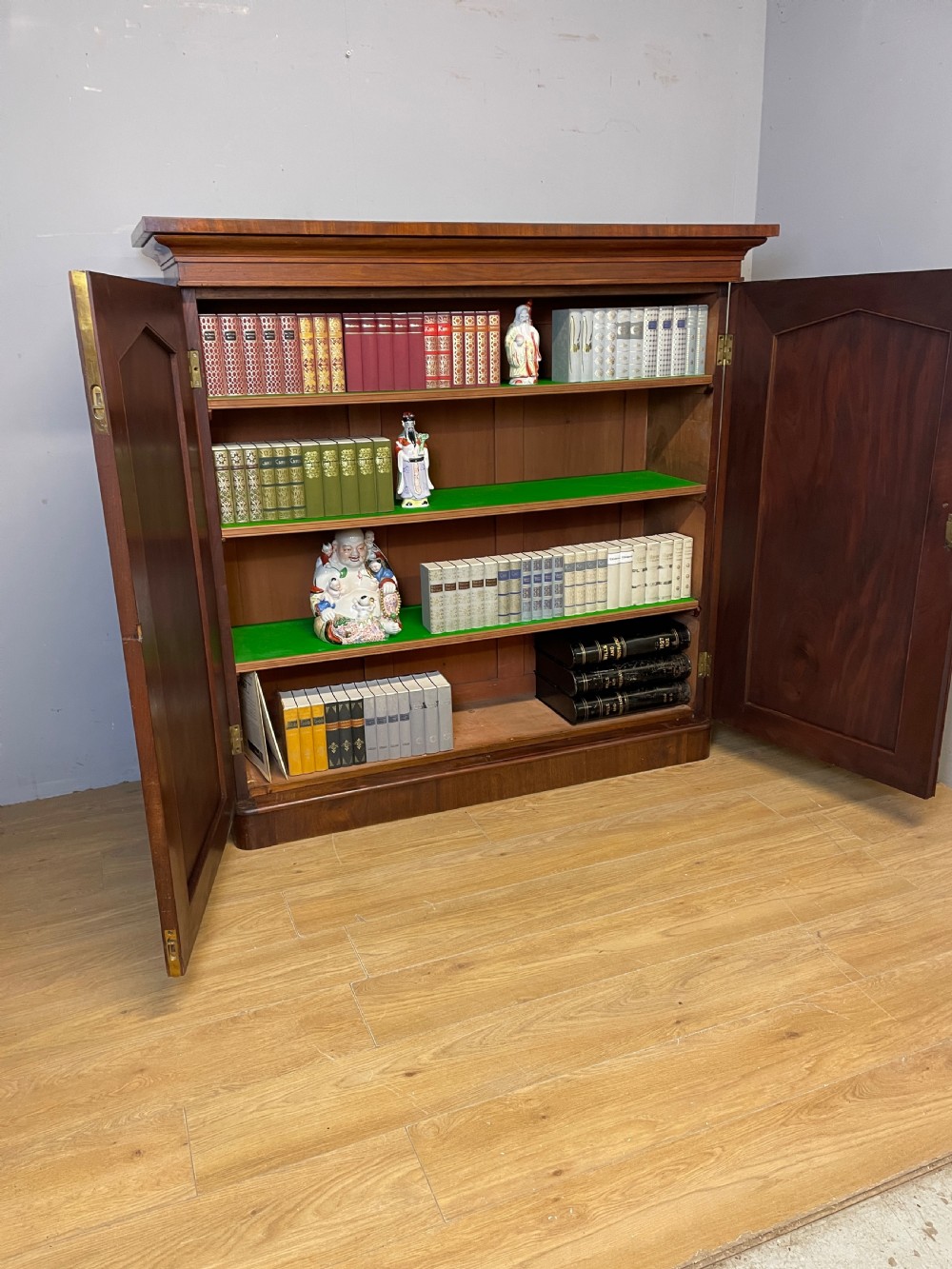 A nineteenth-century flame mahogany two-door library cupboard with arched door panels and a plinth base. View X