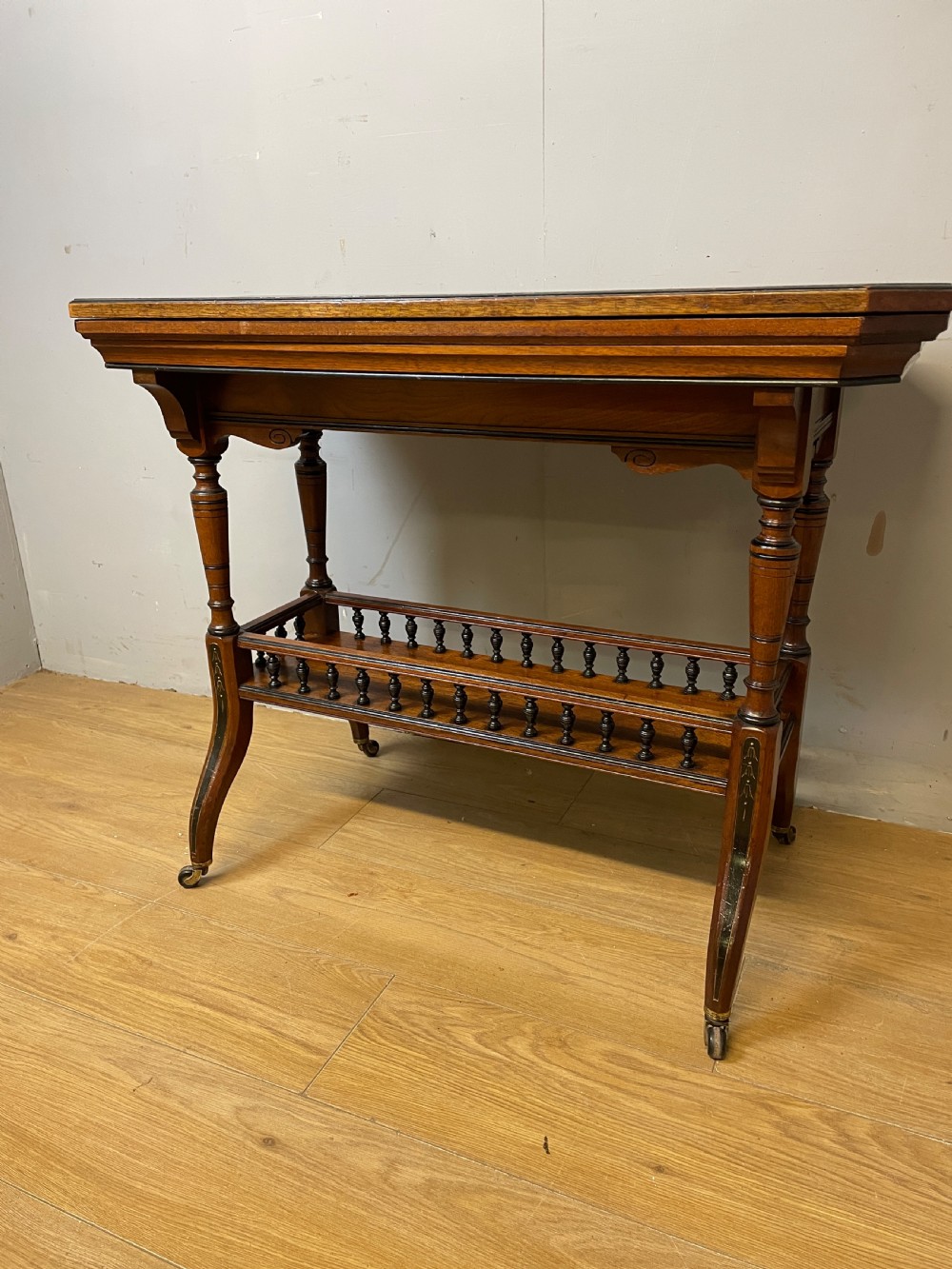 A late 19th-century Aesthetic Movement oak card table with incised top decorations, turned legs, and a lower spindle gallery shelf. View IV