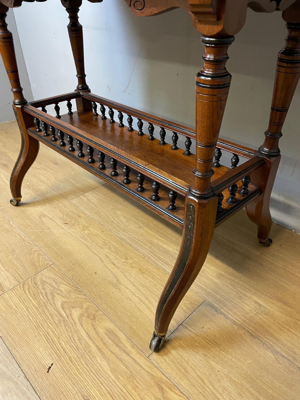 A late 19th-century Aesthetic Movement oak card table with incised top decorations, turned legs, and a lower spindle gallery shelf. View V