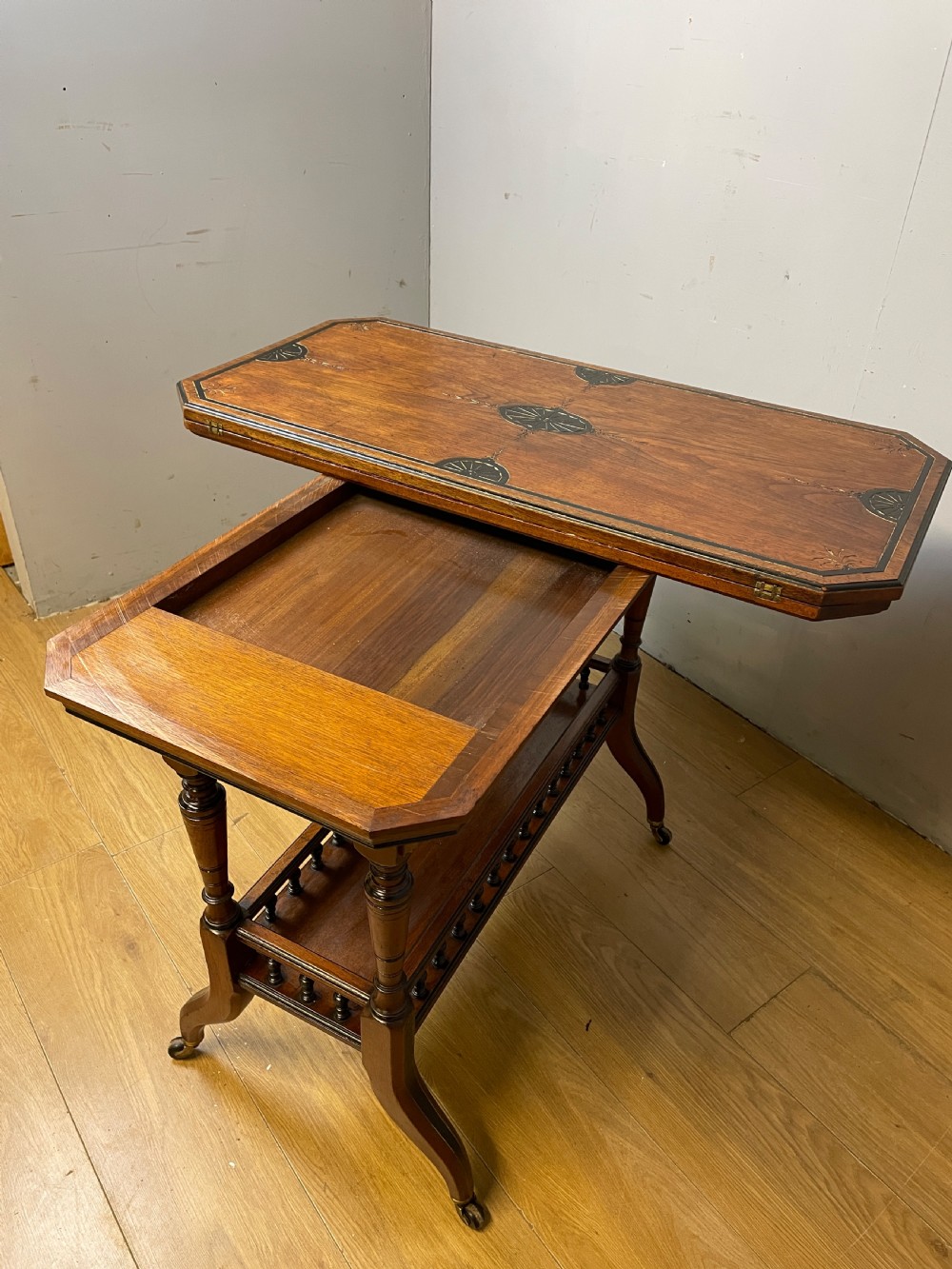 A late 19th-century Aesthetic Movement oak card table with incised top decorations, turned legs, and a lower spindle gallery shelf. View VI