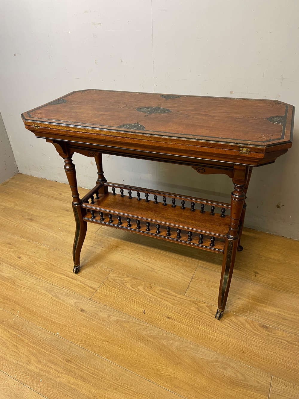 A late 19th-century Aesthetic Movement oak card table with incised top decorations, turned legs, and a lower spindle gallery shelf. View XI