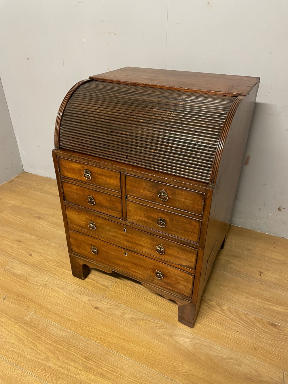 A Georgian mahogany bureau cabinet featuring a curved slatted tambour shutter above four small drawers and two wide drawers with brass handles.