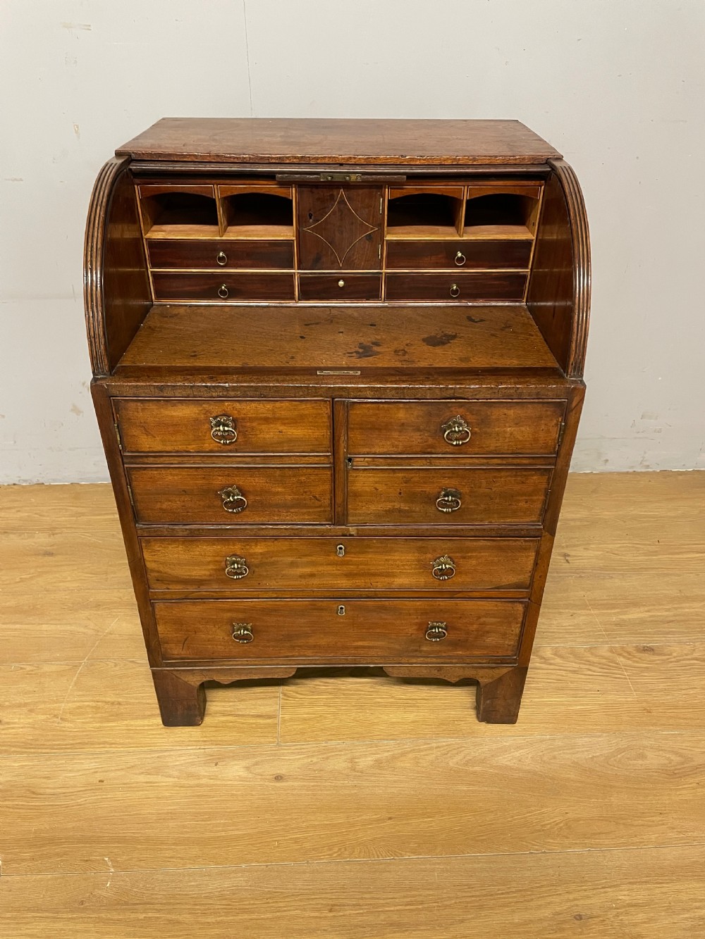 A Georgian mahogany bureau cabinet featuring a curved slatted tambour shutter above four small drawers and two wide drawers with brass handles. View II