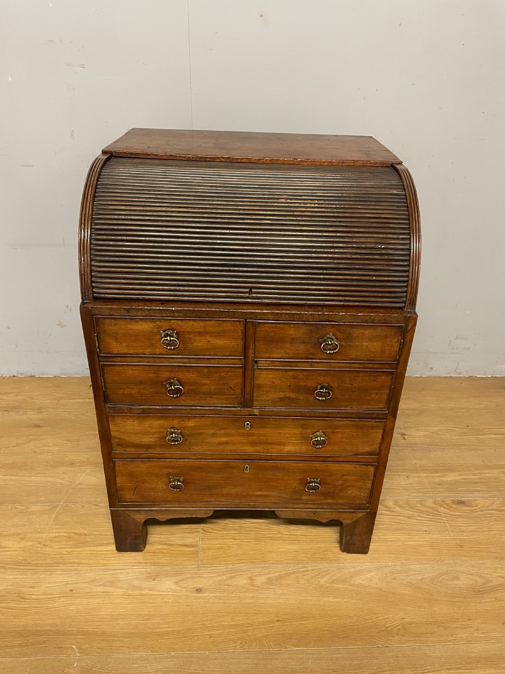 A Georgian mahogany bureau cabinet featuring a curved slatted tambour shutter above four small drawers and two wide drawers with brass handles. View III