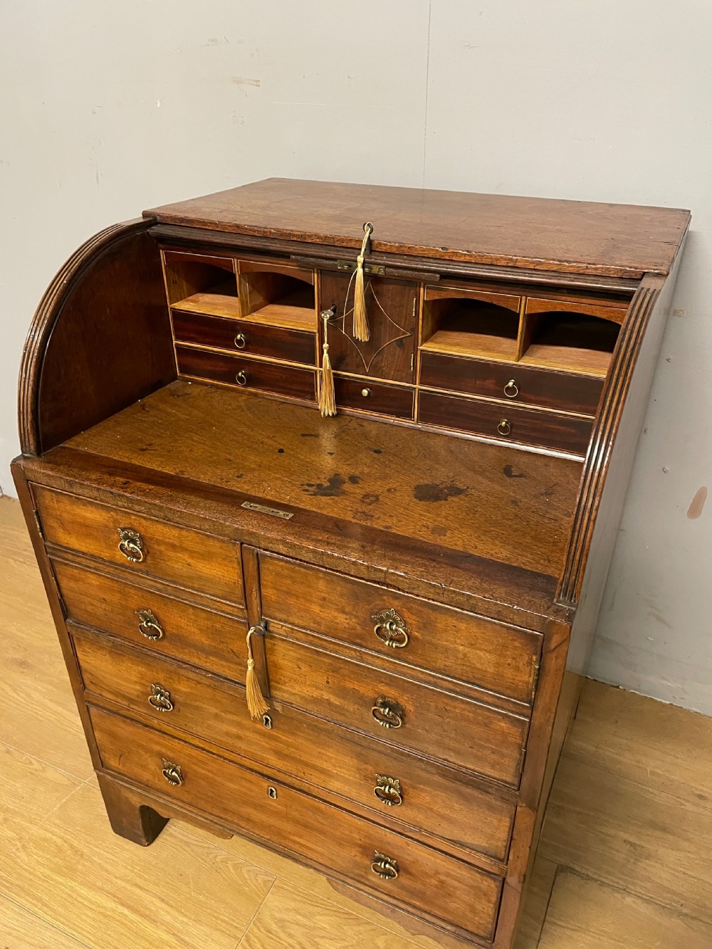 A Georgian mahogany bureau cabinet featuring a curved slatted tambour shutter above four small drawers and two wide drawers with brass handles. View X