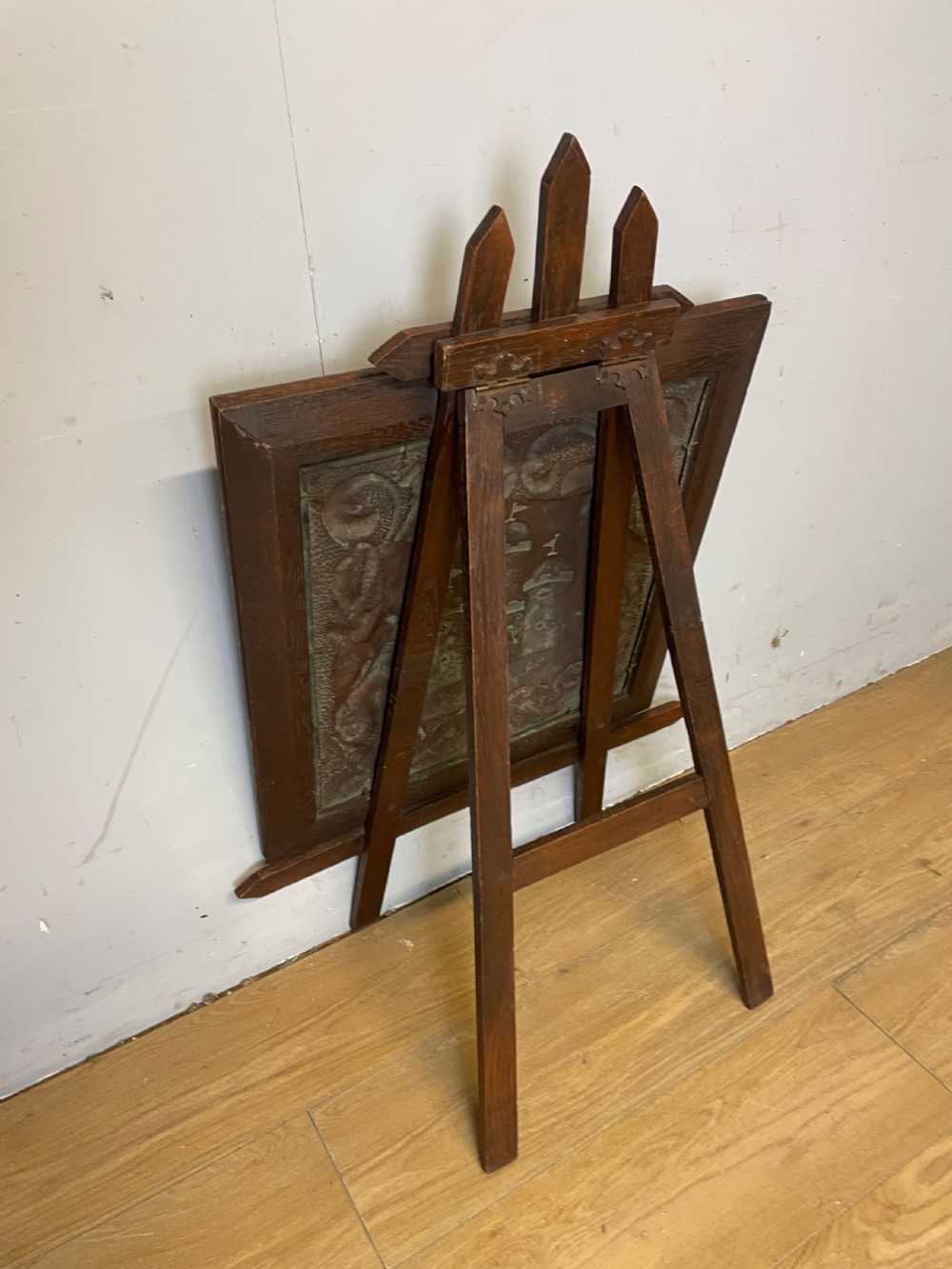 An Arts and Crafts dark oak framed firescreen featuring a central hand-hammered copper panel with an embossed castle motif and scrollwork. View IV