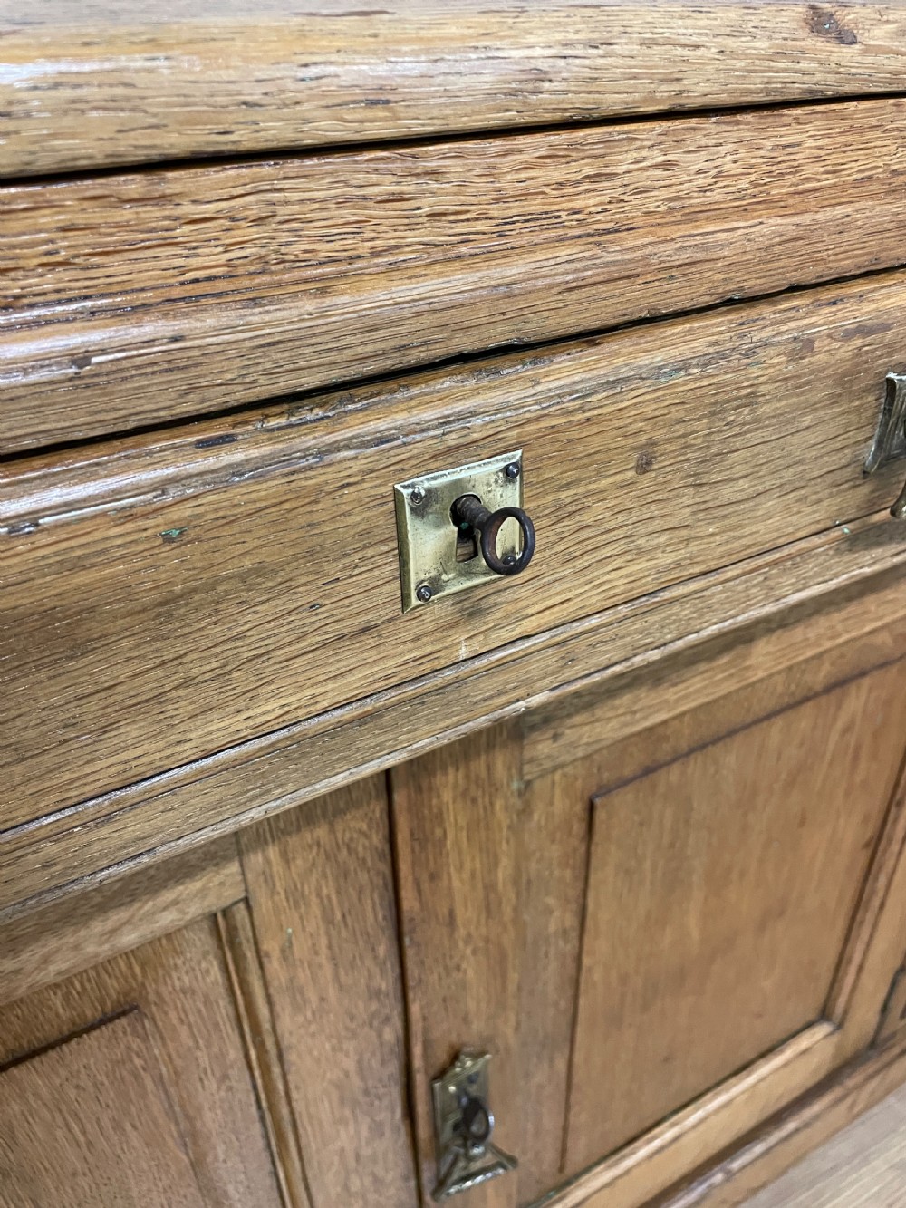 A nineteenth-century golden oak tambour desk featuring multiple side drawers with brass handles, central panelled cupboard doors, and a raised wooden gallery rail. View XIII