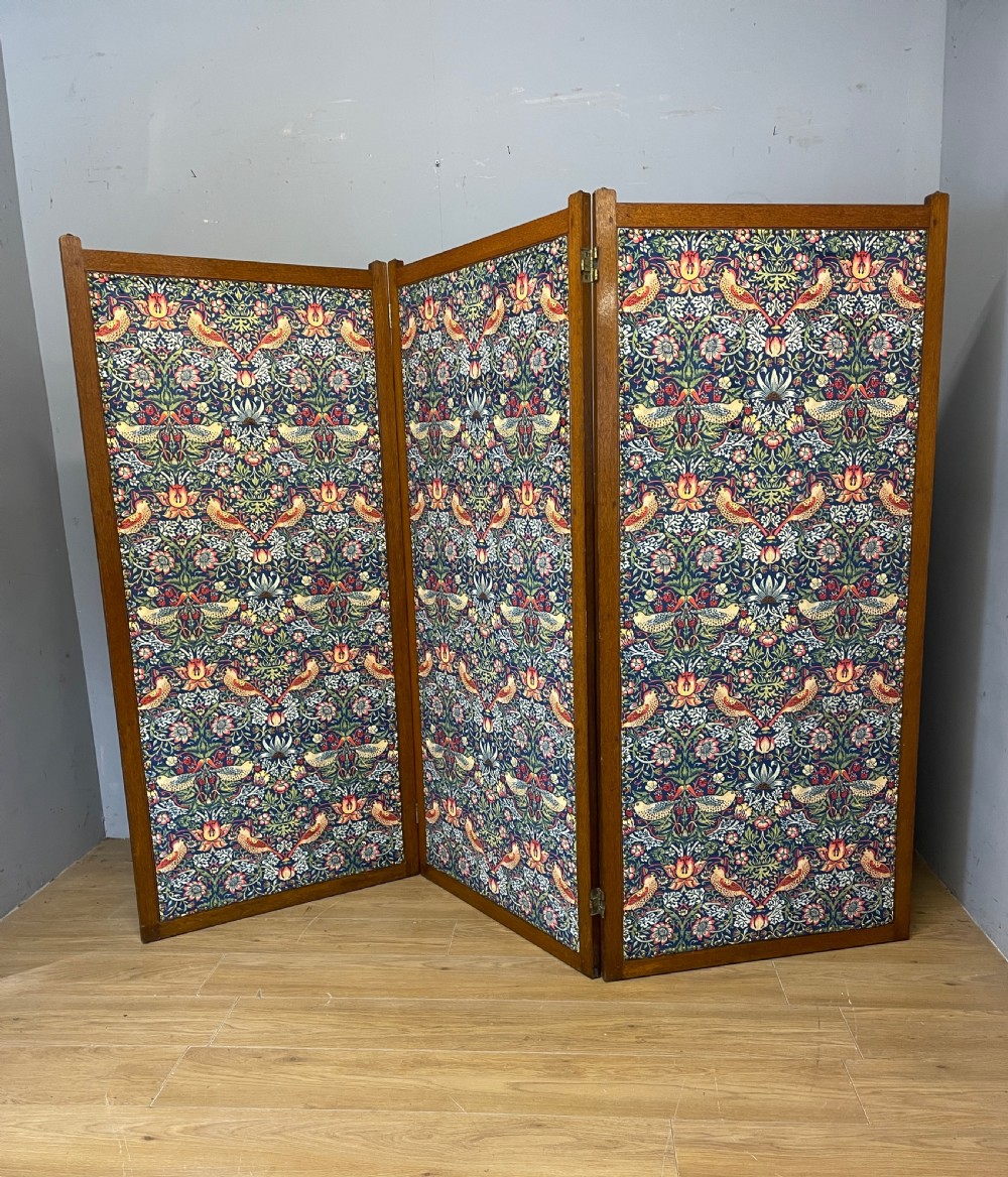 A three-panel wooden folding room screen framed in medium oak and upholstered with William Morris Strawberry Thief pattern velvet fabric in blue, red, and yellow tones. View XIV
