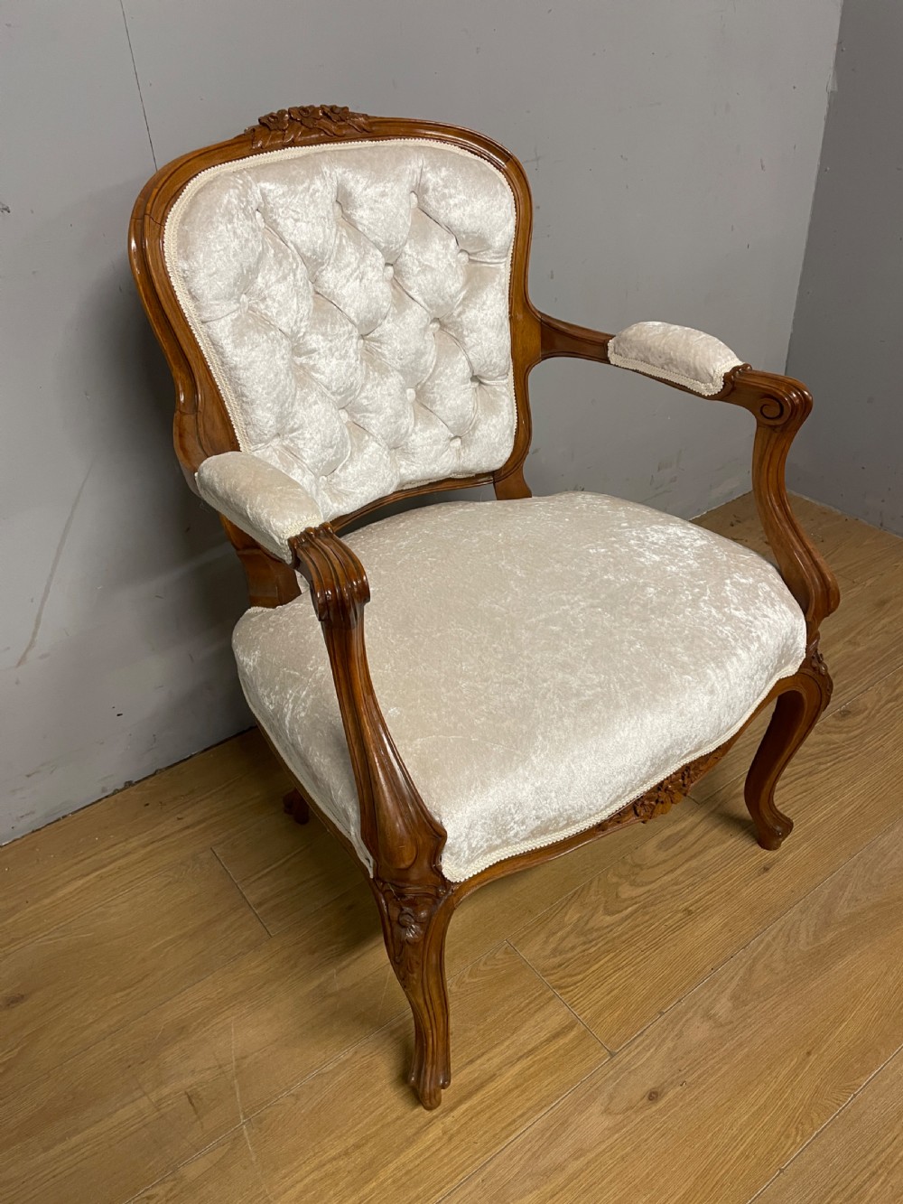 A Louis XV style solid walnut armchair featuring button-tufted cream velvet upholstery, carved cresting, and cabriole legs. View II