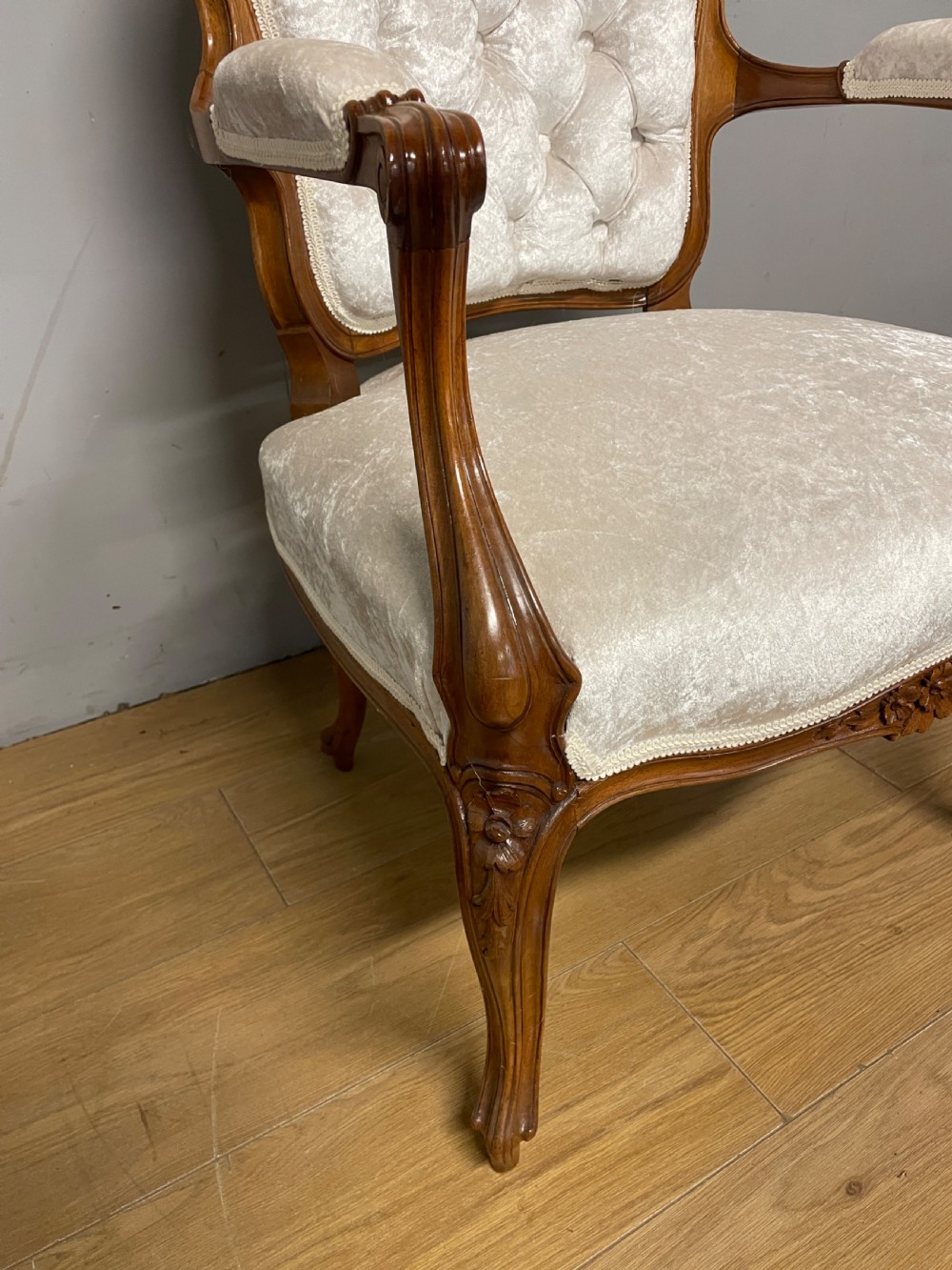 A Louis XV style solid walnut armchair featuring button-tufted cream velvet upholstery, carved cresting, and cabriole legs. View III
