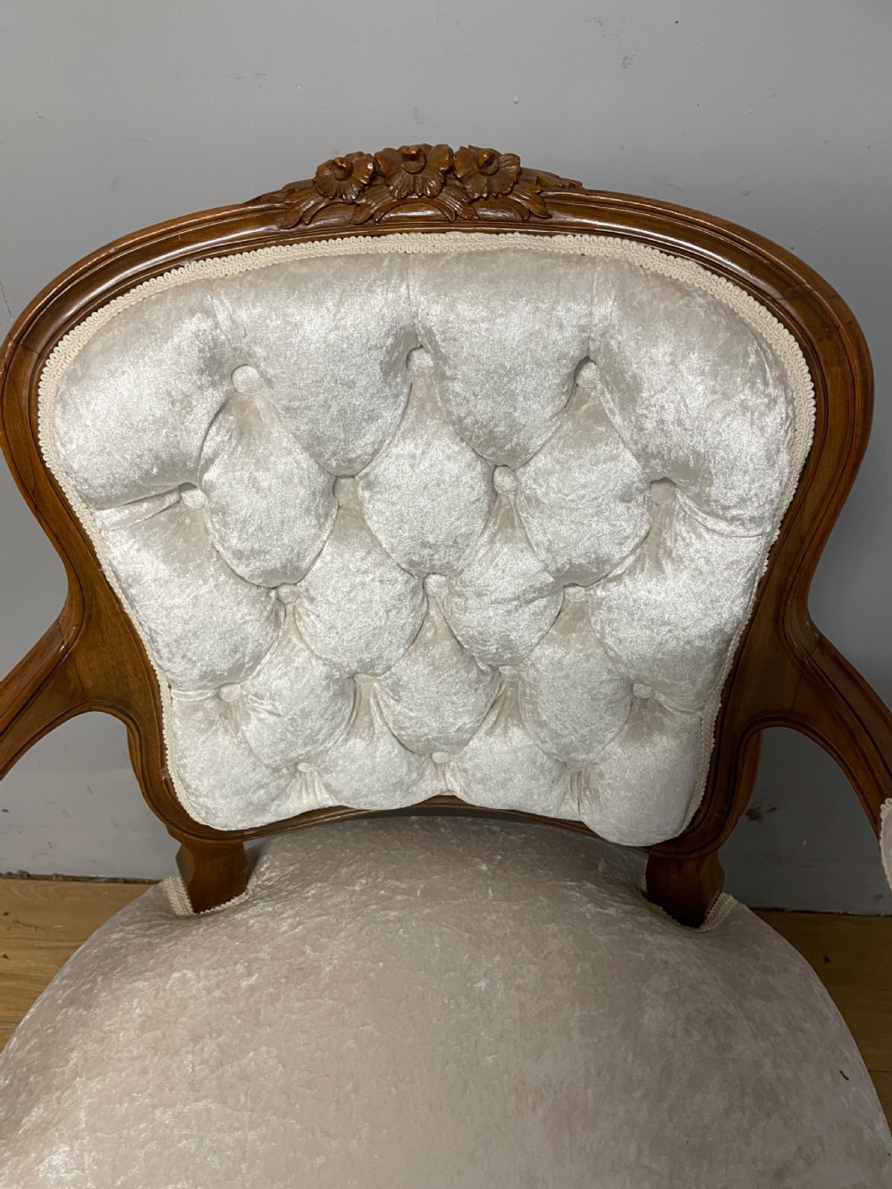 A carved walnut armchair featuring a deep button-tufted cream velvet backrest, padded armrests, and curved cabriole legs. View V