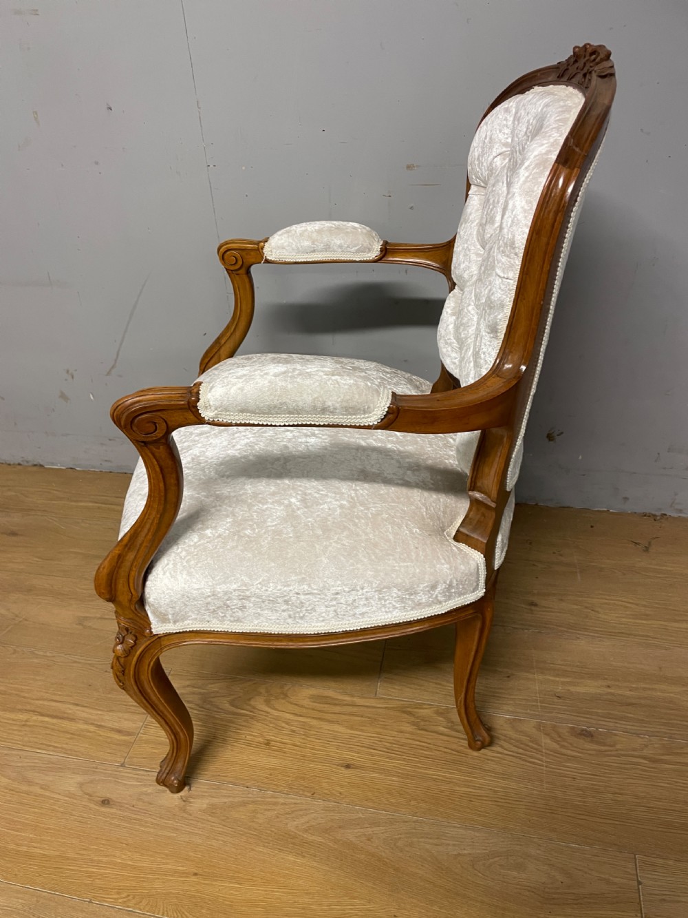 A carved walnut armchair featuring a deep button-tufted cream velvet backrest, padded armrests, and curved cabriole legs. View VII