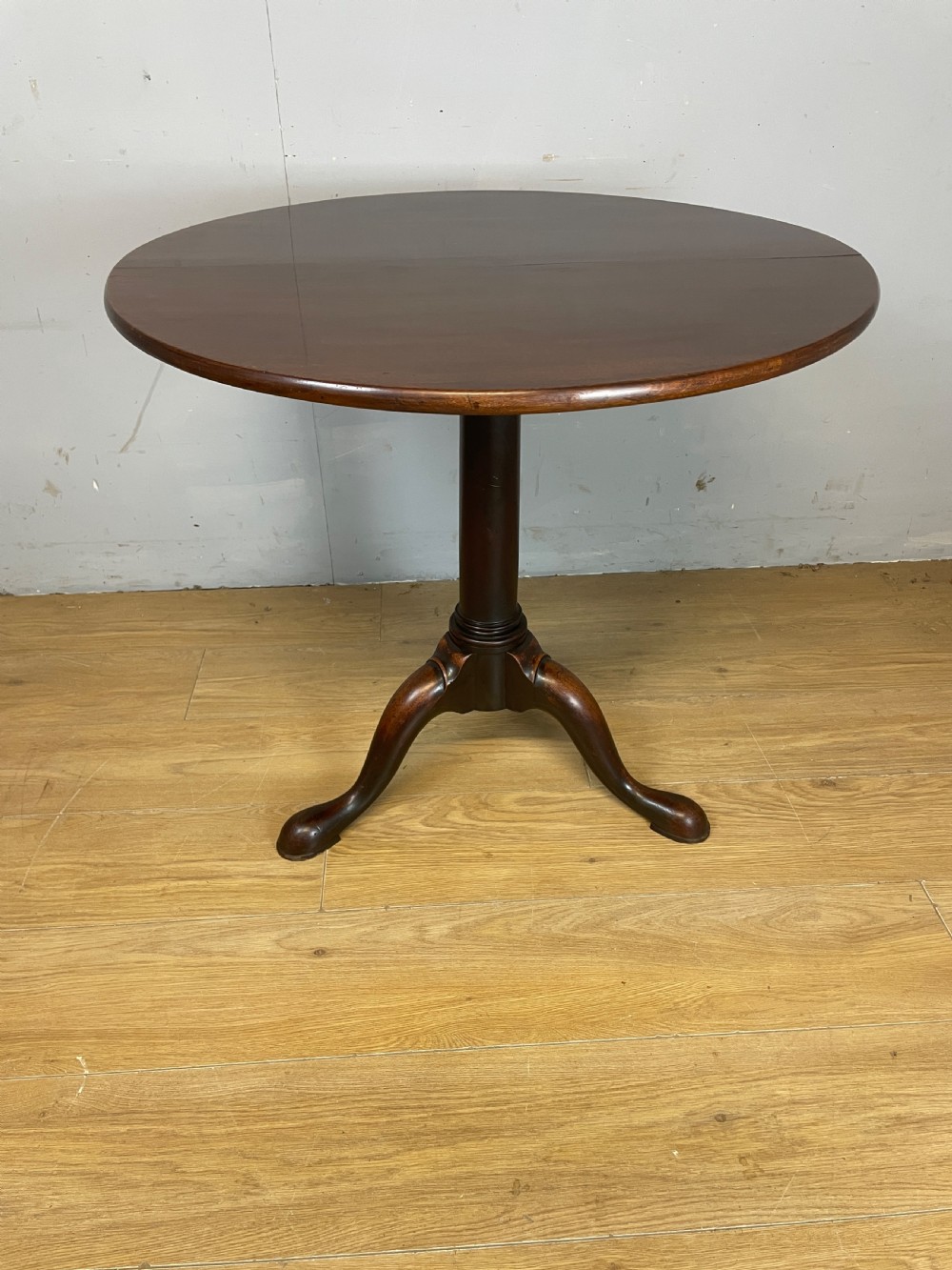 A late eighteenth-century Georgian mahogany tripod table featuring a circular top, a turned gun barrel stem, and three splayed legs.