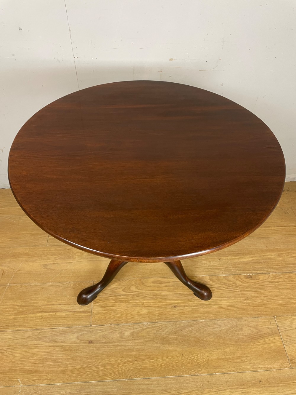 A late eighteenth-century Georgian mahogany tripod table featuring a circular top, a turned gun barrel stem, and three splayed legs. View II