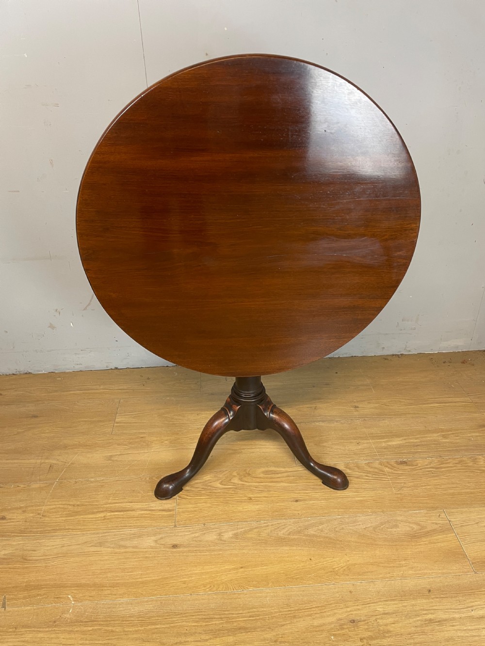 A late eighteenth-century Georgian mahogany tripod table featuring a circular top, a turned gun barrel stem, and three splayed legs. View VI