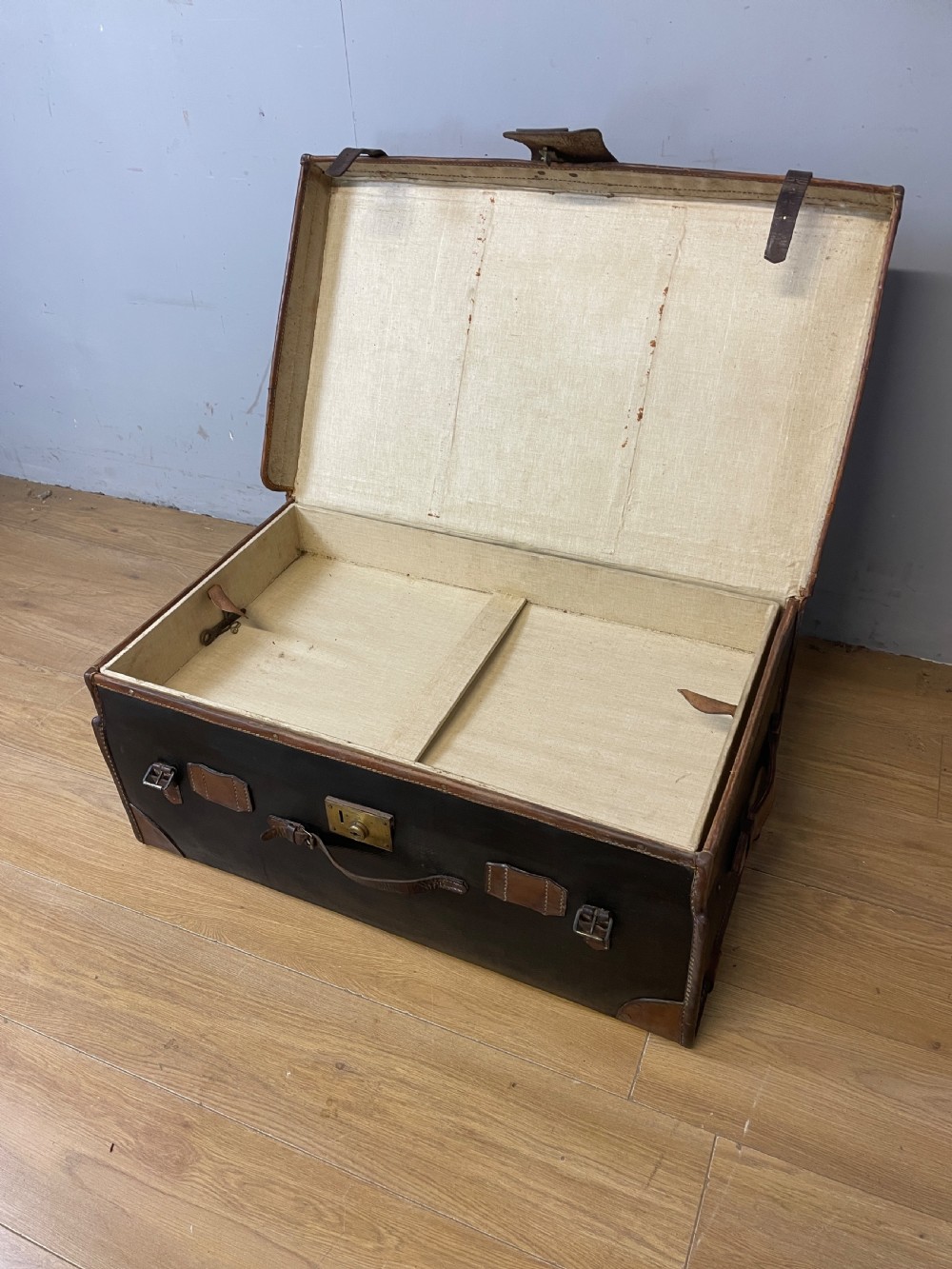 A late 19th-century rectangular black canvas travel trunk featuring brown leather trim, corner protectors, and buckle straps. View III