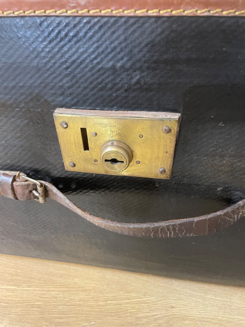 A late 19th-century rectangular black canvas travel trunk featuring brown leather trim, corner protectors, and buckle straps. View V