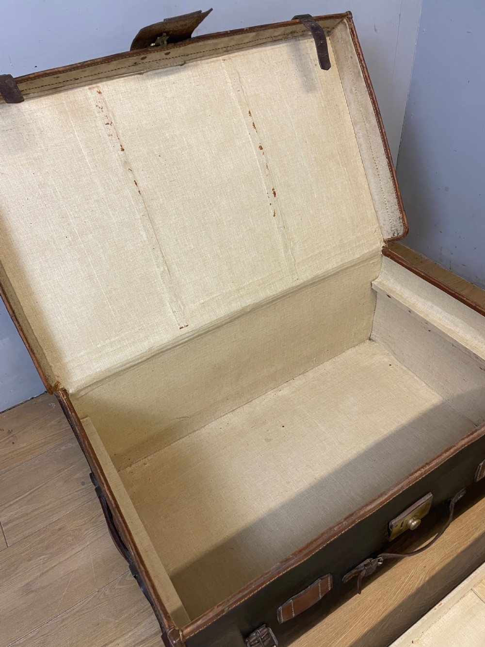A late 19th-century rectangular black canvas travel trunk featuring brown leather trim, corner protectors, and buckle straps. View VII