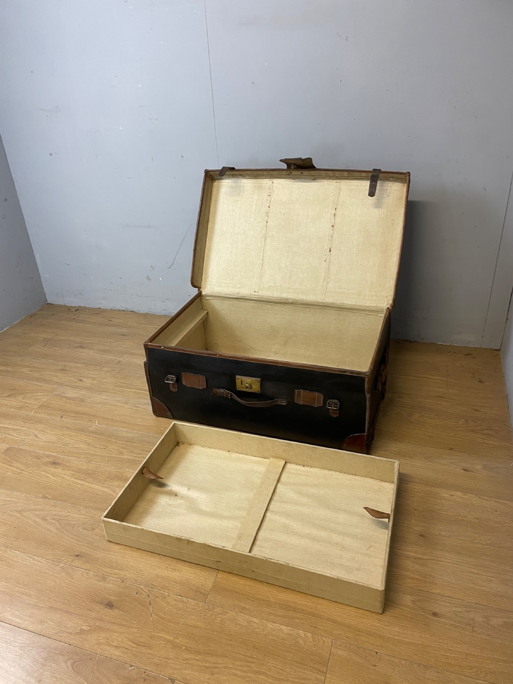 A late 19th-century rectangular black canvas travel trunk featuring brown leather trim, corner protectors, and buckle straps. View VIII