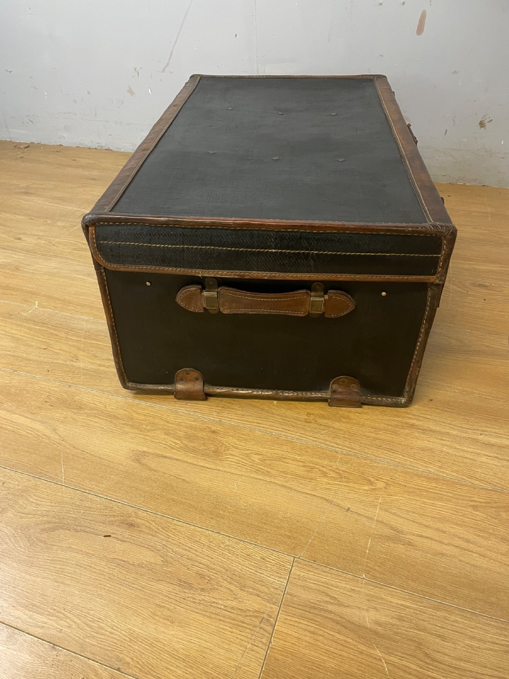 A late 19th-century rectangular black canvas travel trunk featuring brown leather trim, corner protectors, and buckle straps. View IX