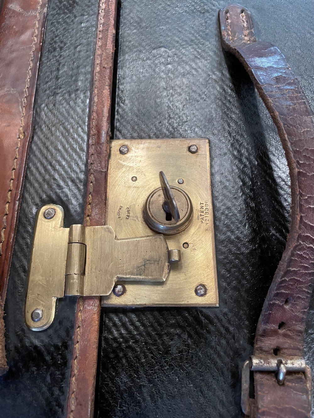 A late 19th-century rectangular black canvas travel trunk featuring brown leather trim, corner protectors, and buckle straps. View XI