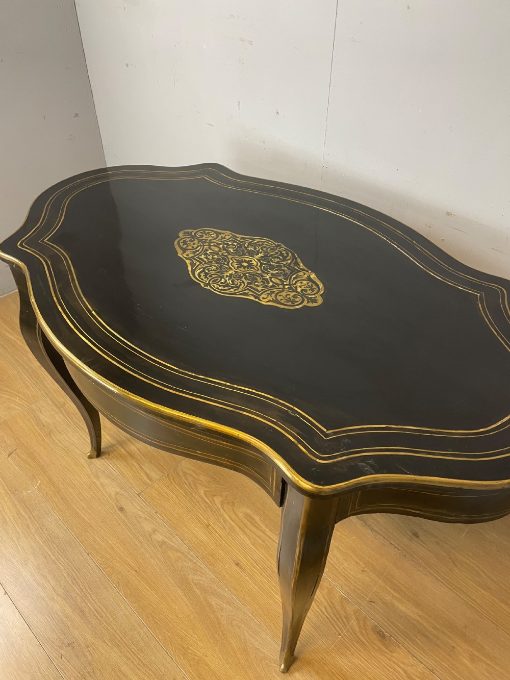 A 19th-century French ebonised writing table featuring brass inlay, a serpentine shaped top, and cabriole legs. View II