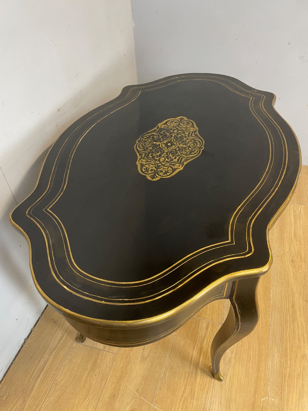 A 19th-century French ebonised writing table featuring brass inlay, a serpentine shaped top, and cabriole legs. View IV