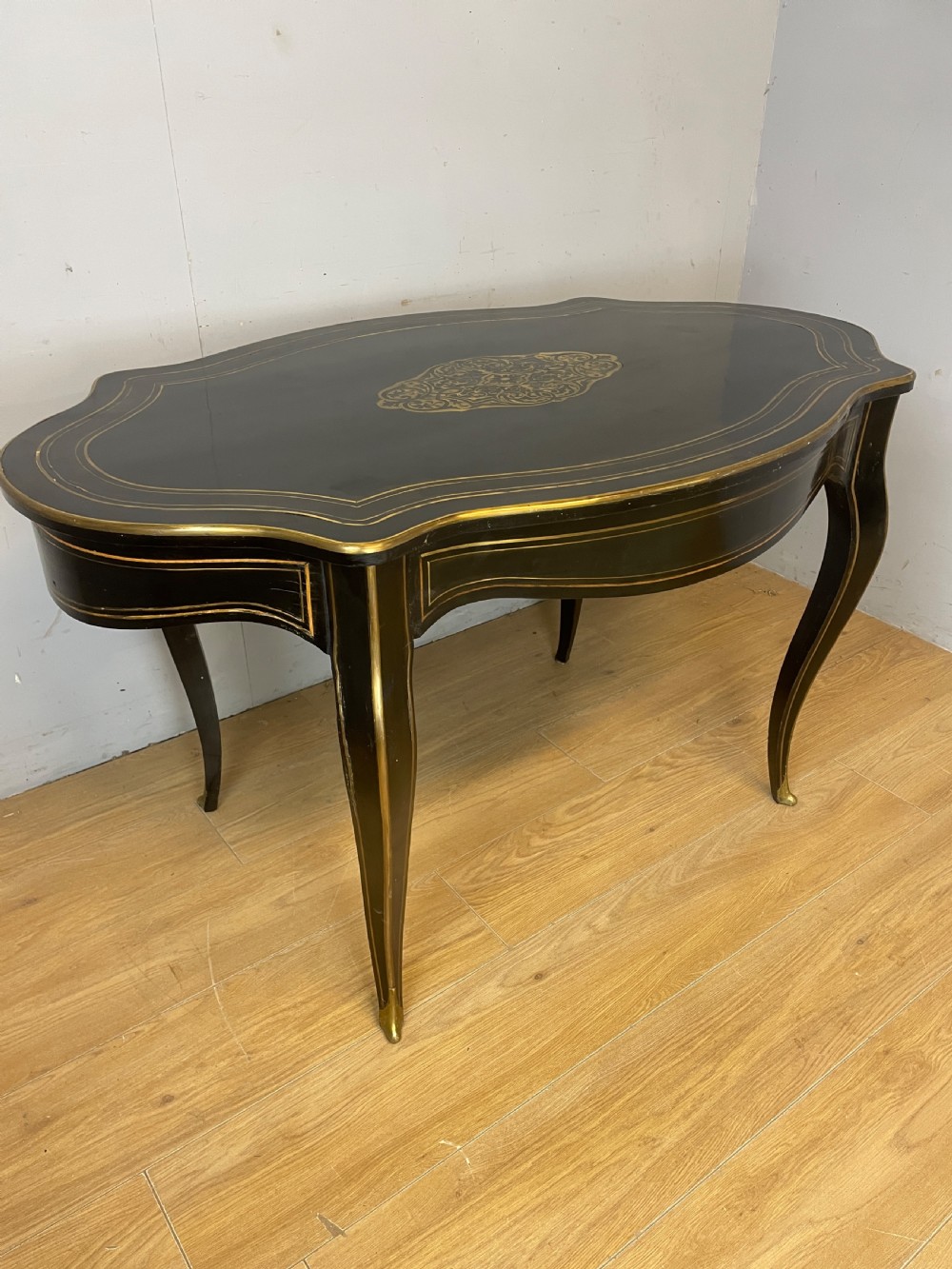 A 19th-century French ebonised writing table featuring brass inlay, a serpentine shaped top, and cabriole legs. View V