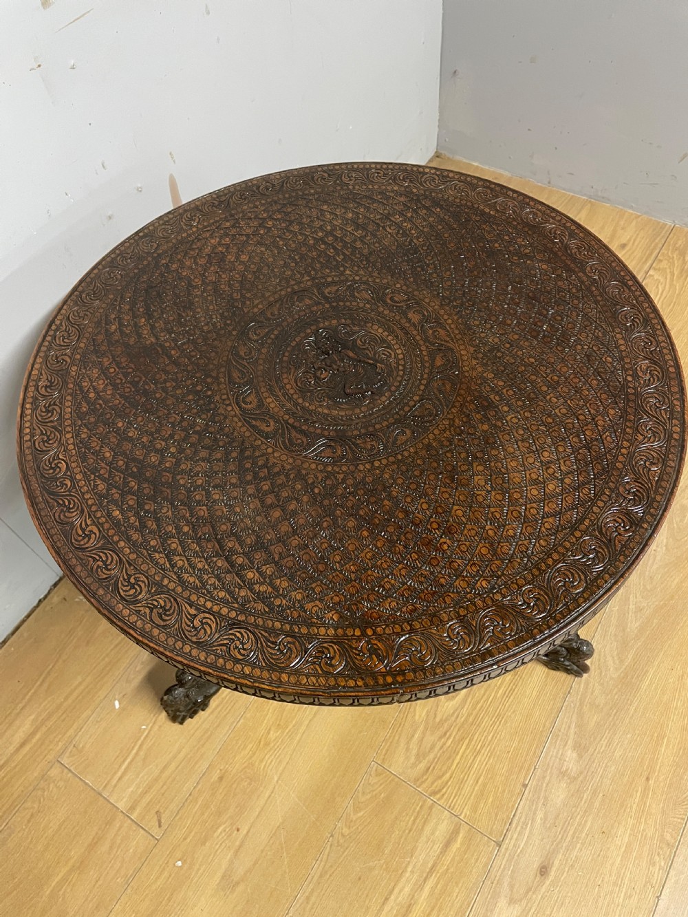 A circular 19th-century Anglo-Indian dark wood side table with intricate hand-carved floral patterns on the tabletop and cabriole legs. View II
