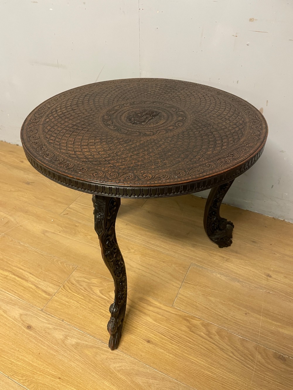 A circular 19th-century Anglo-Indian dark wood side table with intricate hand-carved floral patterns on the tabletop and cabriole legs. View III