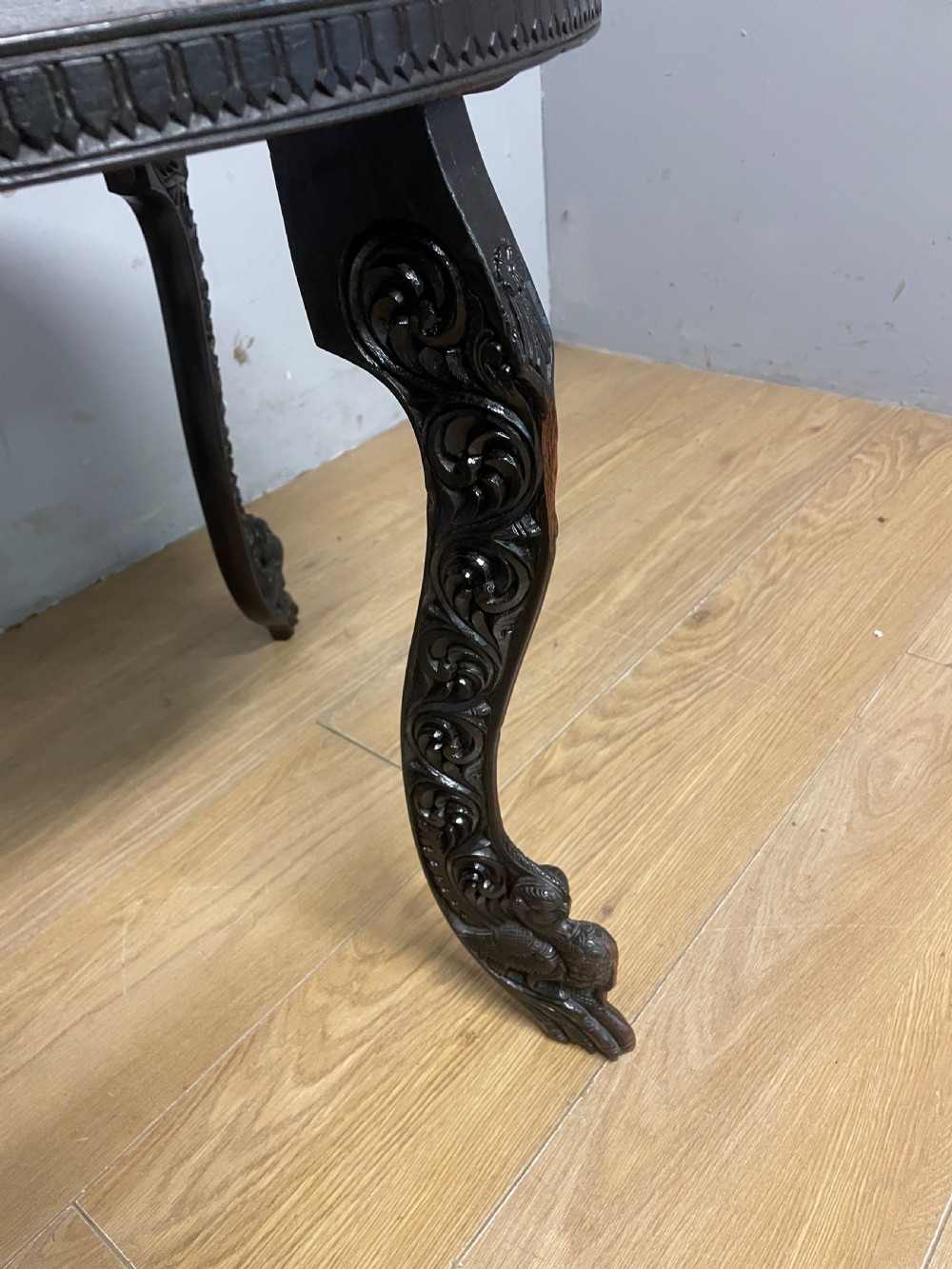 A circular 19th-century Anglo-Indian dark wood side table with intricate hand-carved floral patterns on the tabletop and cabriole legs. View IV