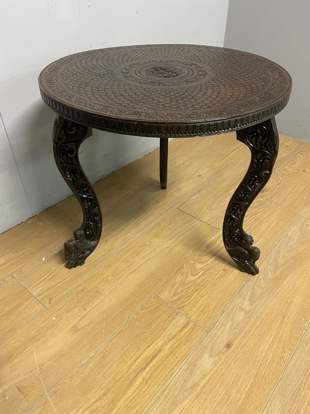 A circular 19th-century Anglo-Indian dark wood side table with intricate hand-carved floral patterns on the tabletop and cabriole legs. View V