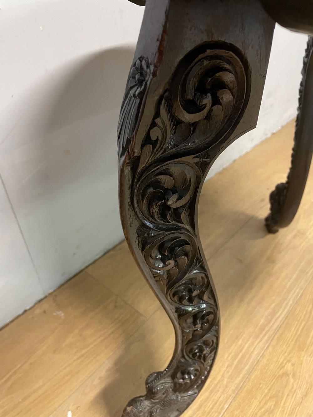 A circular 19th-century Anglo-Indian dark wood side table with intricate hand-carved floral patterns on the tabletop and cabriole legs. View VI