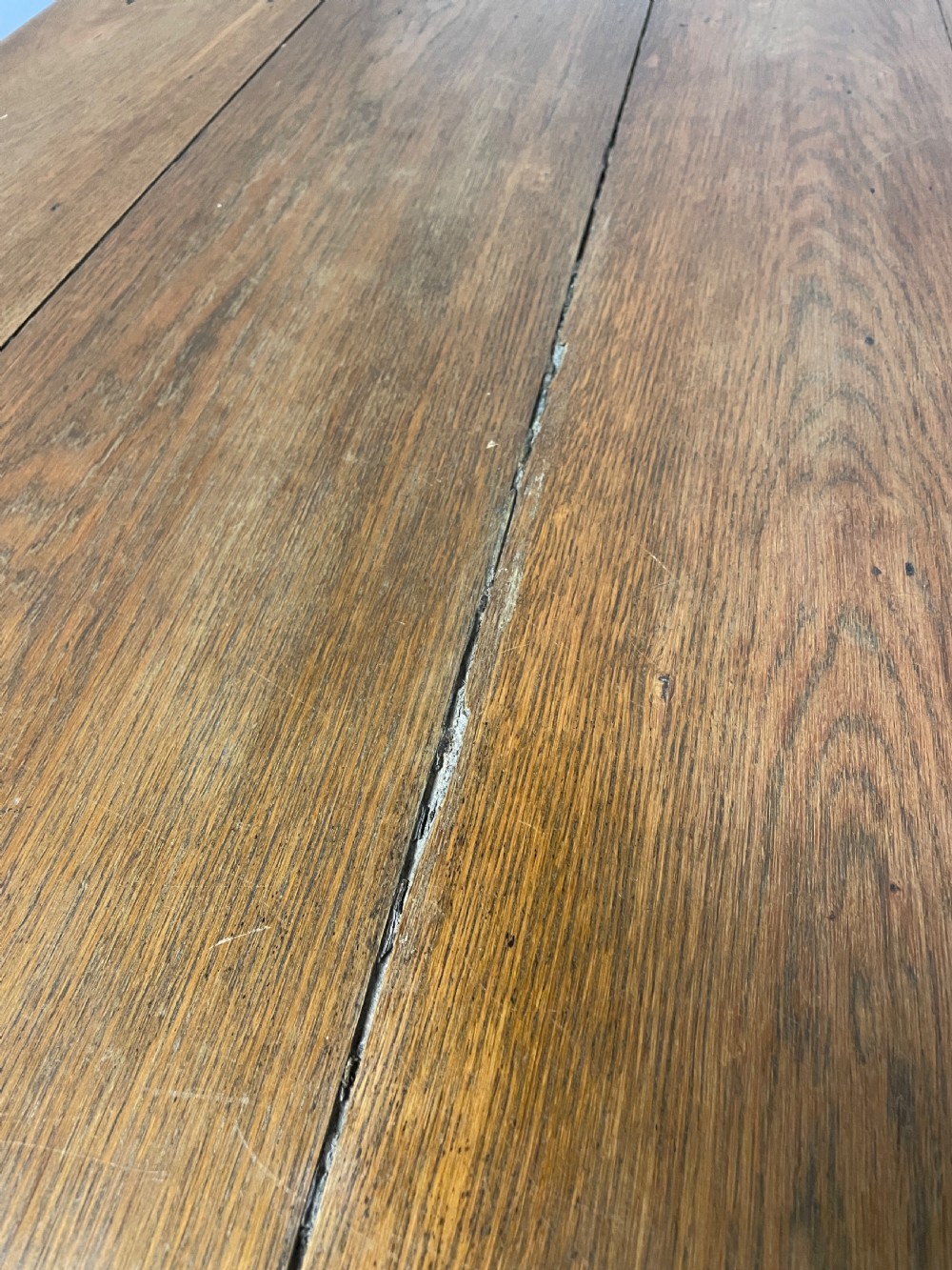 An Arts and Crafts oak refectory dining table featuring a rectangular top supported by shaped trestle end supports connected by a stretcher. View X