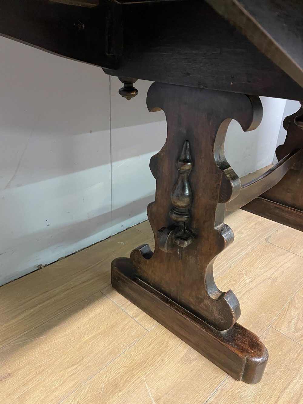 An Arts and Crafts oak refectory dining table featuring a rectangular top supported by shaped trestle end supports connected by a stretcher. View XI