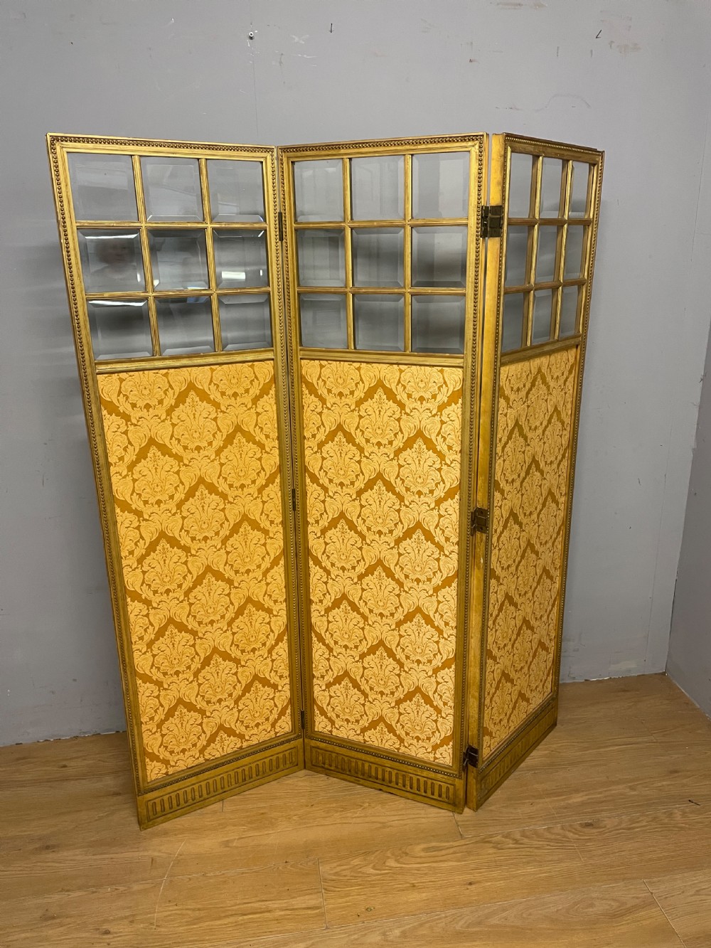 A nineteenth-century three-panel giltwood folding screen featuring glazed upper window panes and golden damask upholstered lower sections. View II