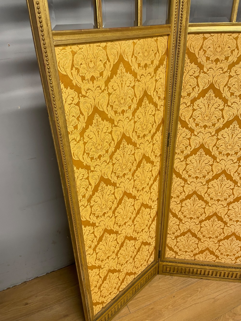 A nineteenth-century three-panel giltwood folding screen featuring glazed upper window panes and golden damask upholstered lower sections. View IV