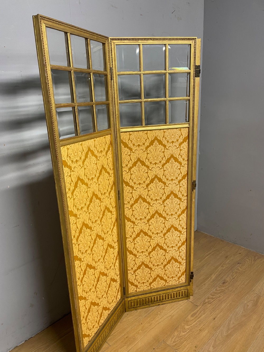 A nineteenth-century three-panel giltwood folding screen featuring glazed upper window panes and golden damask upholstered lower sections. View V