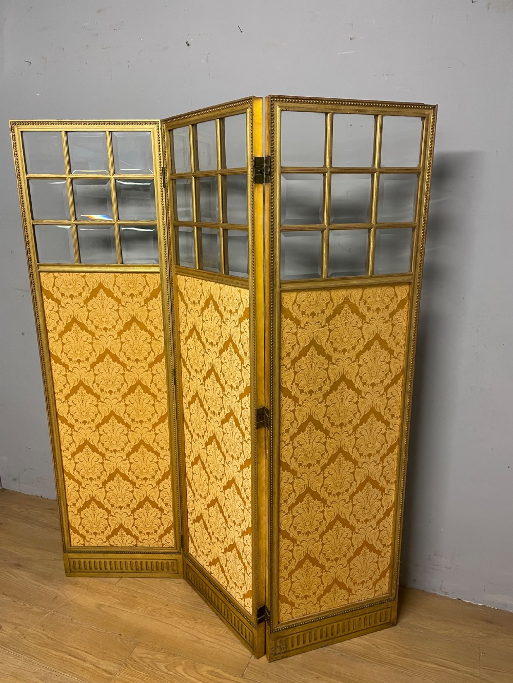 A nineteenth-century three-panel giltwood folding screen featuring glazed upper window panes and golden damask upholstered lower sections. View VII