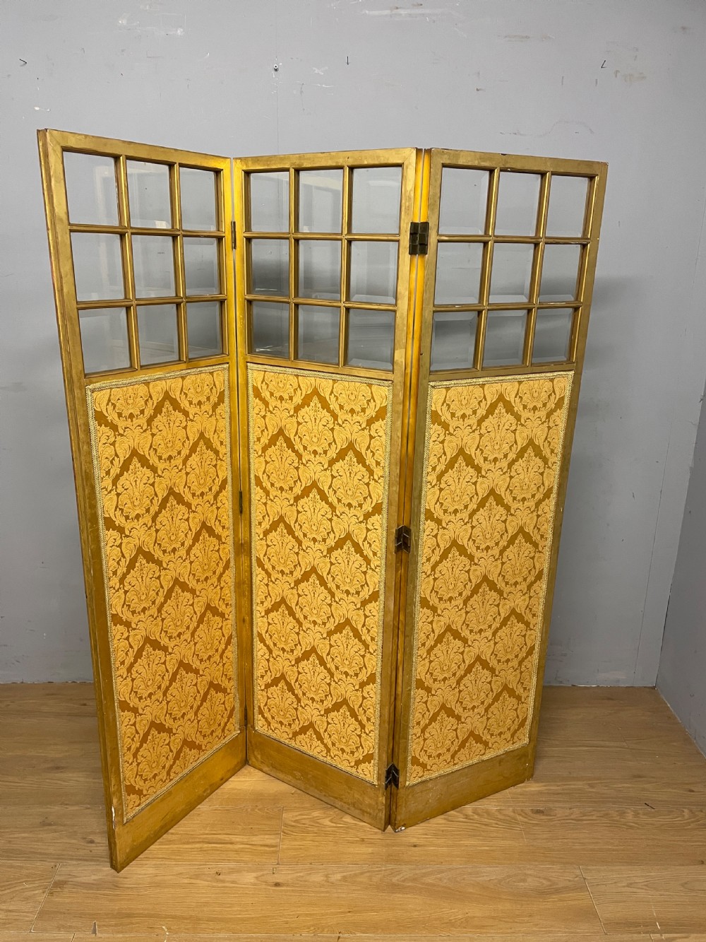 A nineteenth-century three-panel giltwood folding screen featuring glazed upper window panes and golden damask upholstered lower sections. View VIII