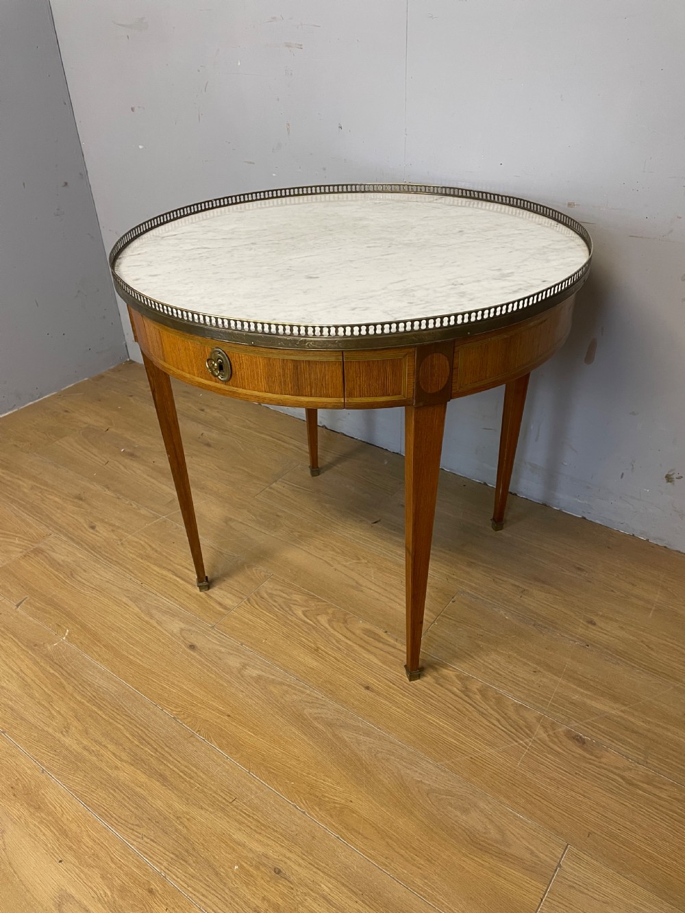 A late 19th-century French circular Bouillotte table featuring a white marble top with a pierced brass gallery, a veneered apron with a small drawer, and four square tapered legs ending in brass sabots. View III