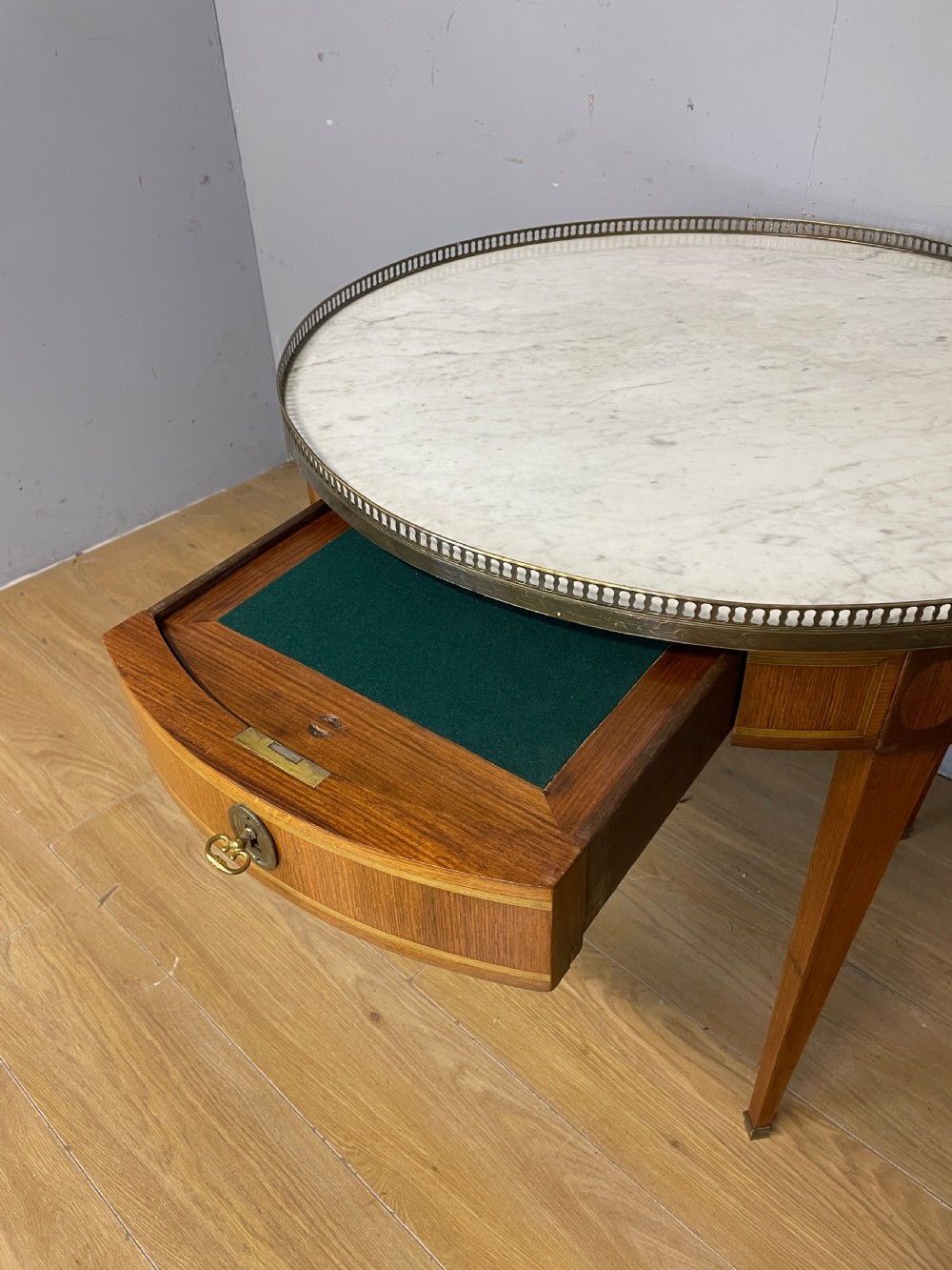 A late 19th-century French circular Bouillotte table featuring a white marble top with a pierced brass gallery, a veneered apron with a small drawer, and four square tapered legs ending in brass sabots. View IV