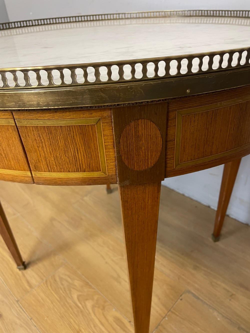 A late 19th-century French circular Bouillotte table featuring a white marble top with a pierced brass gallery, a veneered apron with a small drawer, and four square tapered legs ending in brass sabots. View IX
